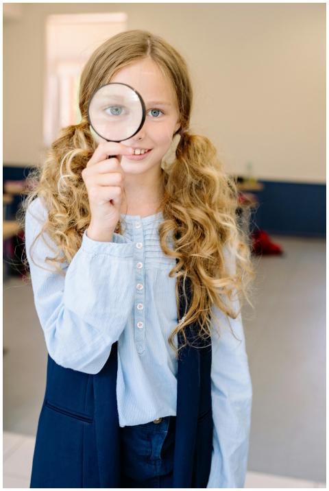 Smiling young girl with magnifying glass explores