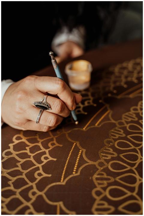 Close-up of a hand creating intricate dot painting
