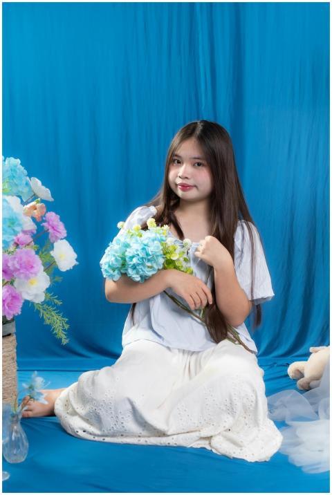 Young woman sitting with blue hydrangeas in a colo