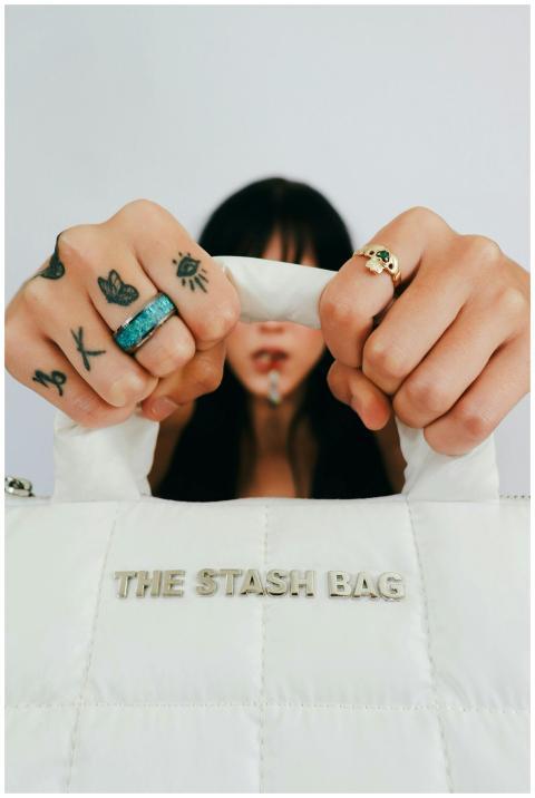 Close-up of woman showcasing stylish bag and tatto