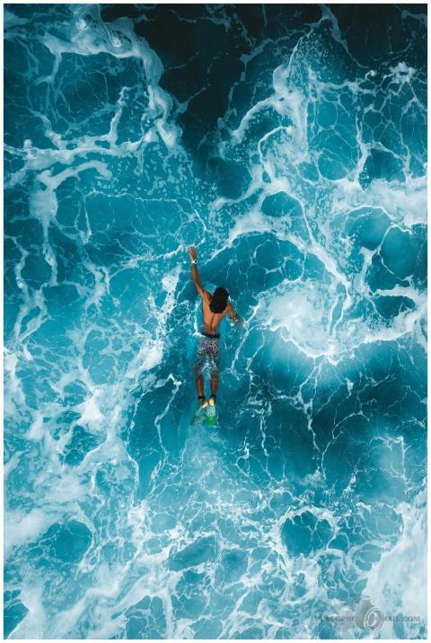 Aerial photo of surfer navigating bright blue ocea