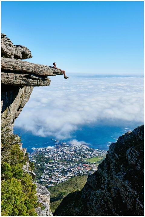 A person sits on a cliff edge enjoying a breathtak