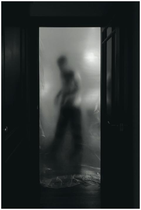 Eerie silhouette behind a door, creating a ghostly