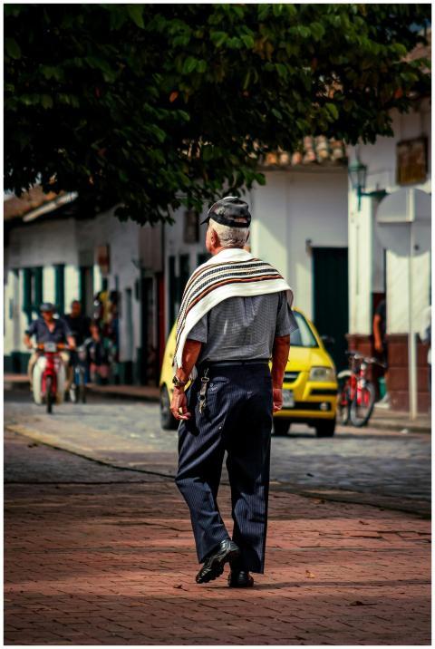 An elderly man wearing traditional clothing walks