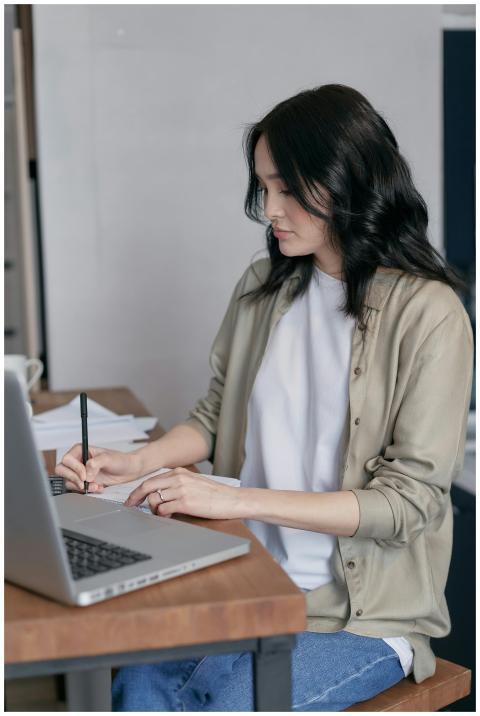 A woman sitting at a desk writing in a notebook ne