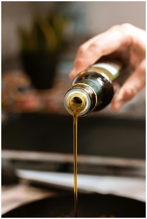 A close-up shot of olive oil being poured into a p