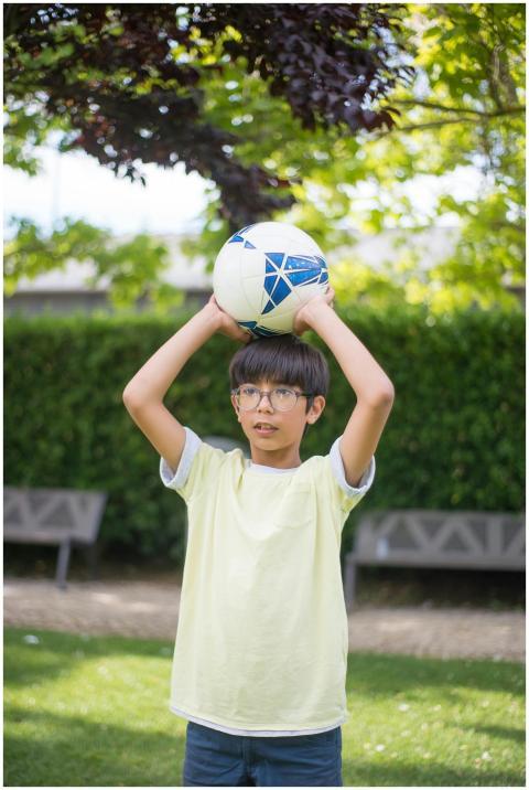 A young boy holds a soccer ball over his head in a