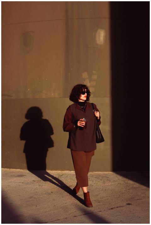 Fashionable woman in brown attire strolls with dri