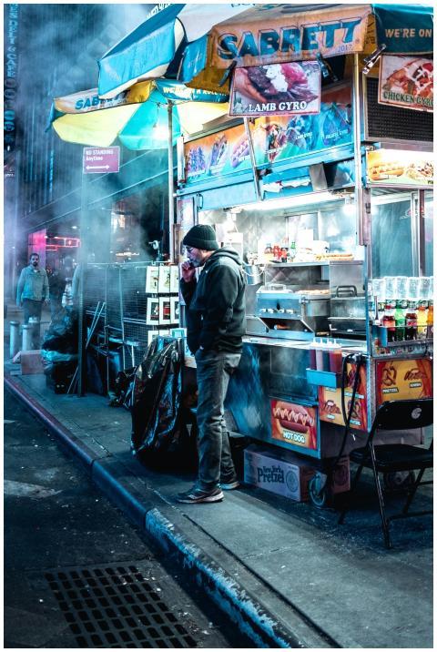 Street food stall in NYC at night with a vendor in