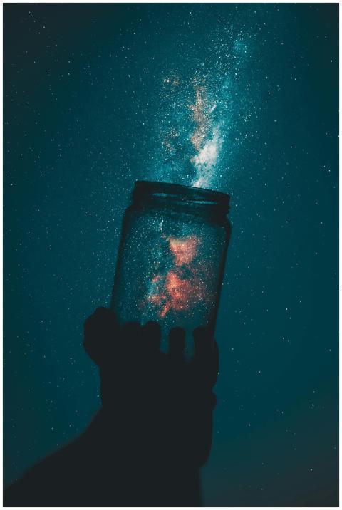A silhouette hand holds a mason jar capturing a st