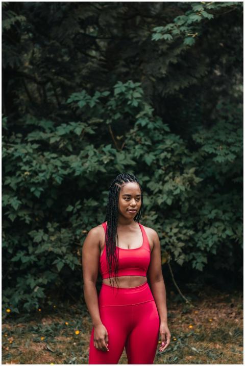 Smiling black woman in red activewear standing out