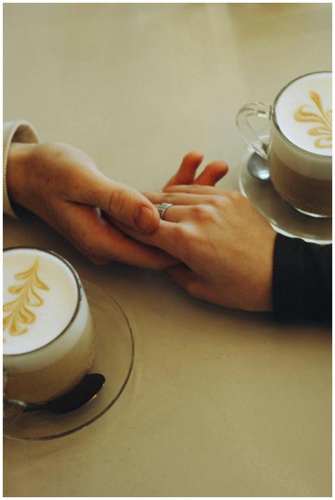 A couple holding hands over lattes with beautiful