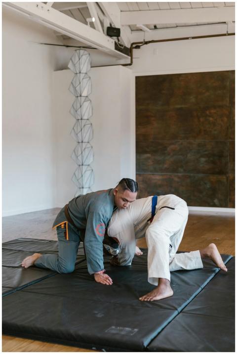 Two men practicing martial arts on floor mat in a