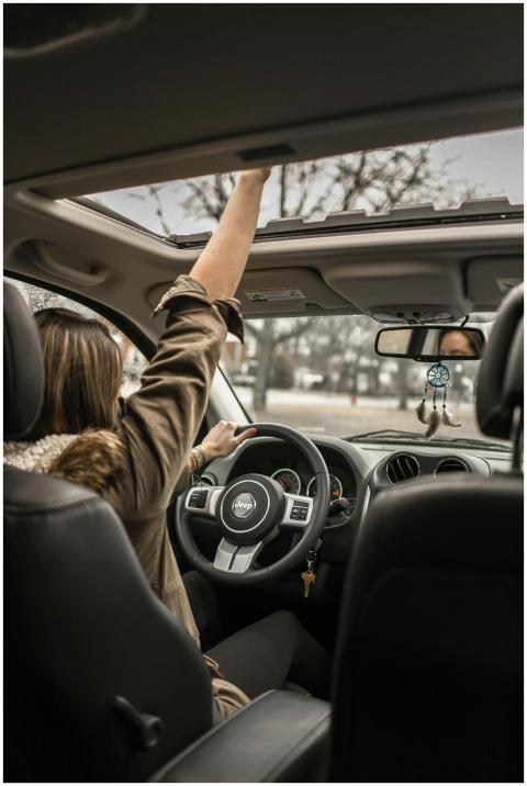 A young woman enjoying a drive with the sunroof op