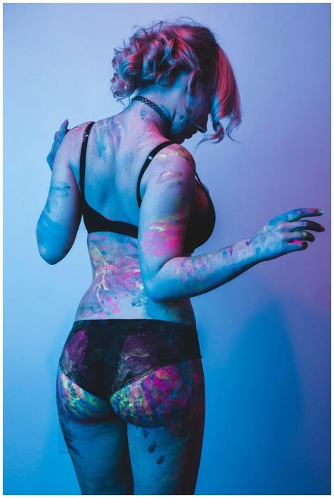 Back view of a woman with neon paint in lingerie,