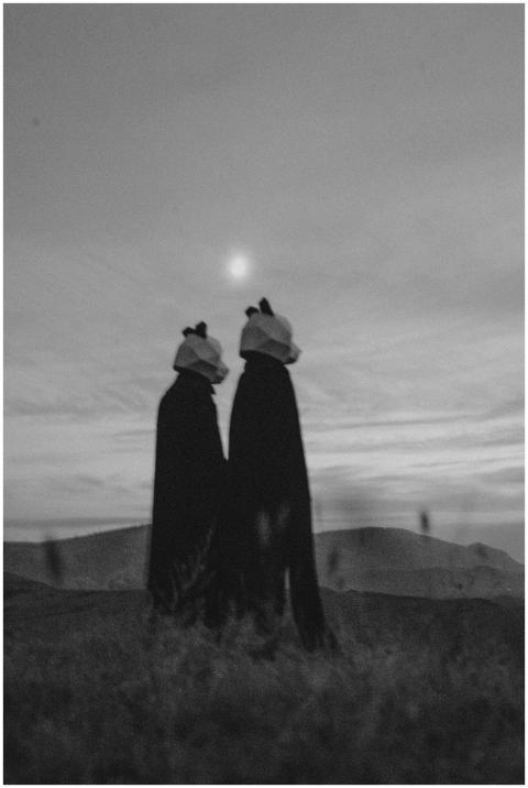 Two figures in panda costumes stand silhouetted ag