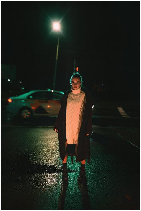 Woman posing in stylish outfit on a wet city stree