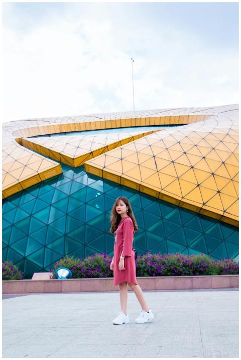 Stylish young woman poses in front of modern glass
