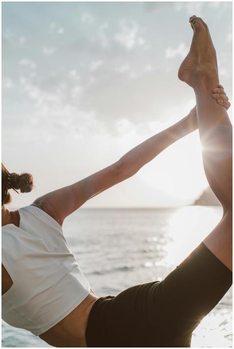 A woman in a yoga pose at sunset by the ocean, emb