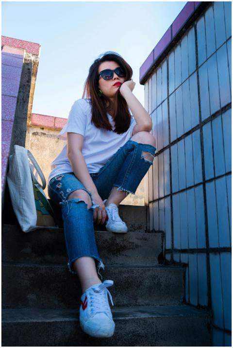 A stylish woman in sunglasses and casual attire si