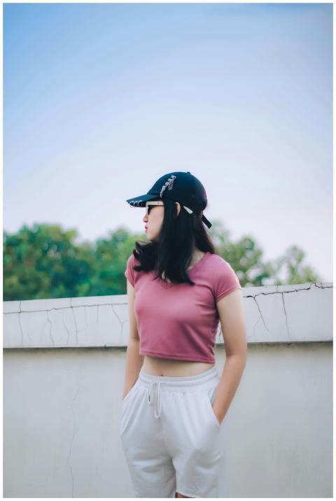Young woman wearing a crop top and cap, posing out