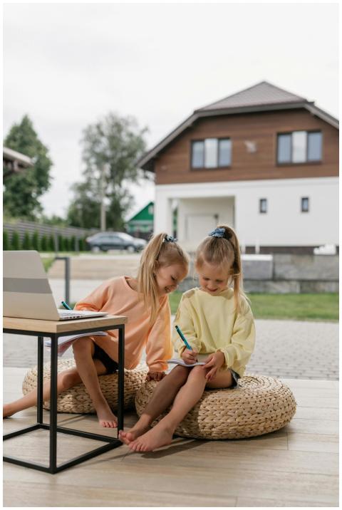 Two young girls study together using a laptop, sit