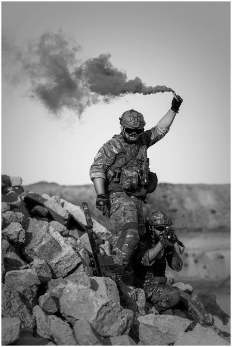 Two soldiers in action with smoke signal in rocky