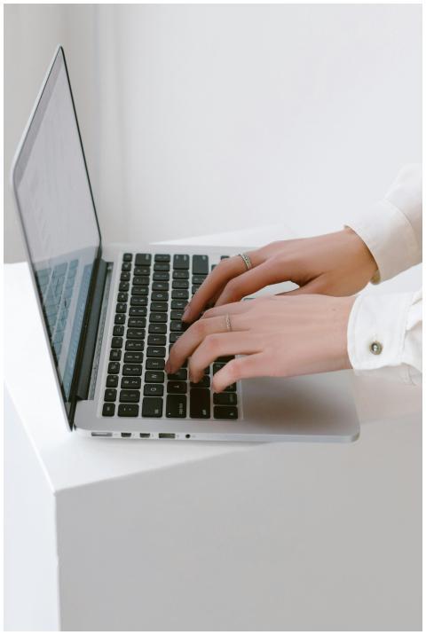 Close-up of hands typing on a laptop in a bright,
