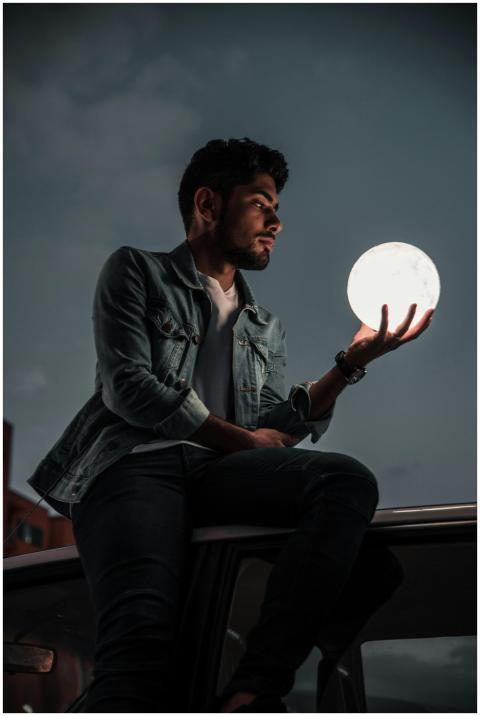 Man sitting on car roof holding an illuminated sph