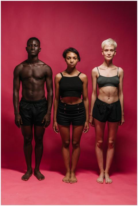 A diverse group of three individuals posing agains