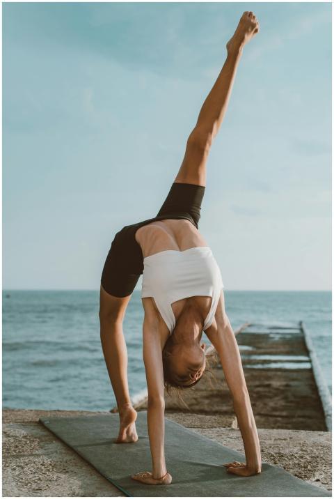 A woman performs a yoga handstand by the seaside,