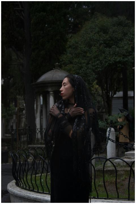 Woman in black veil stands in a haunting cemetery