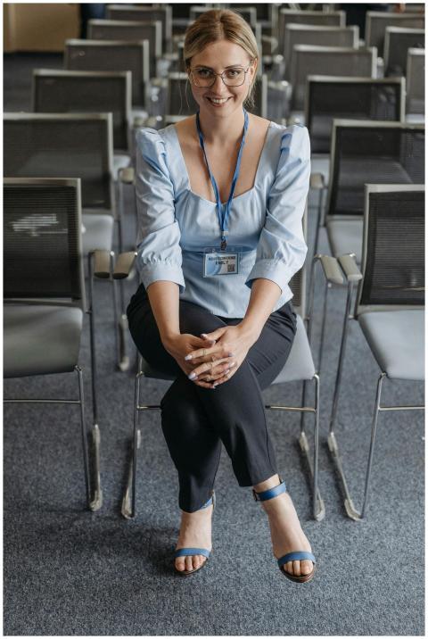 Smiling woman in blue top seated in empty conferen