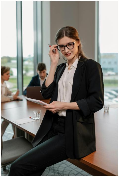 Professional woman in black blazer posing in offic