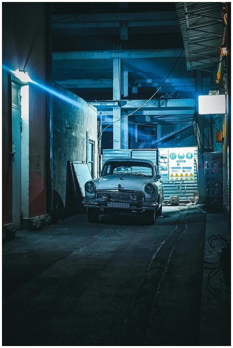 A classic vintage car parked in a dimly lit urban