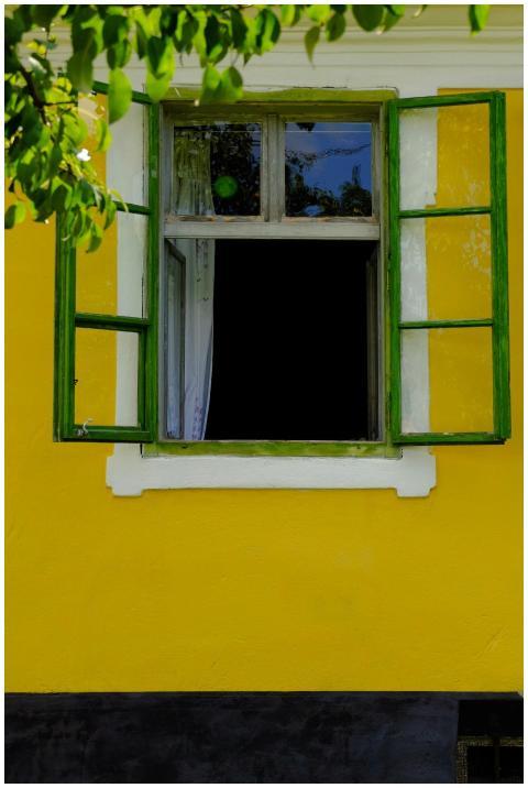 Bright yellow house with open green-framed window,