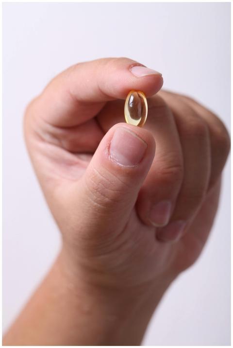 A hand gently holding a capsule, symbolizing healt