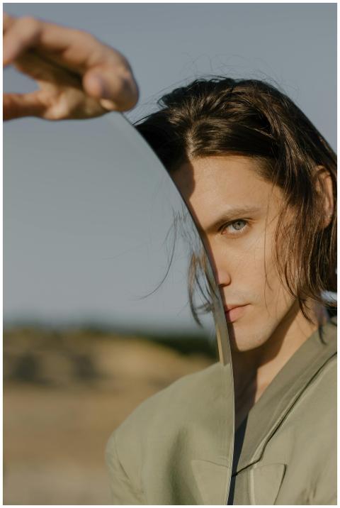 A creative portrait of a man holding a mirror outd