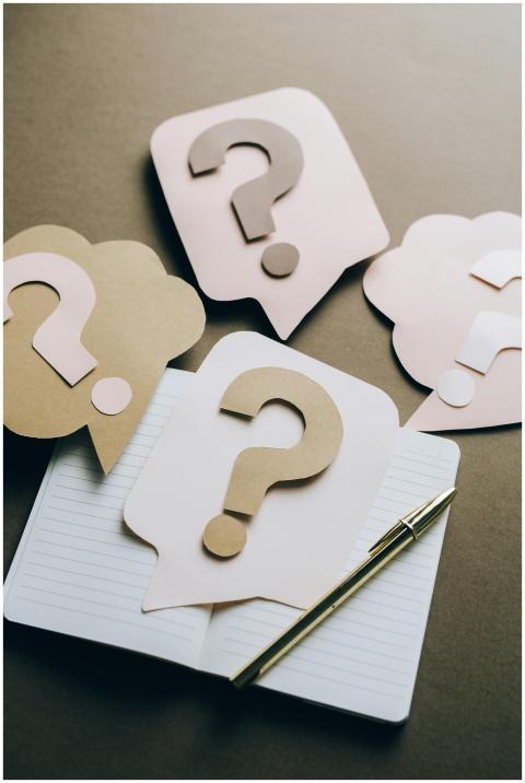 Artistic paper question marks on an open notebook