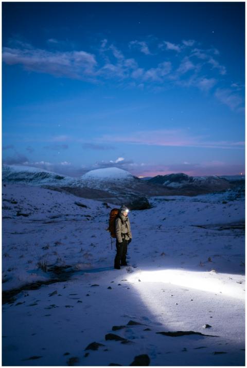 Hiker with headlamp trekking through snowy terrain