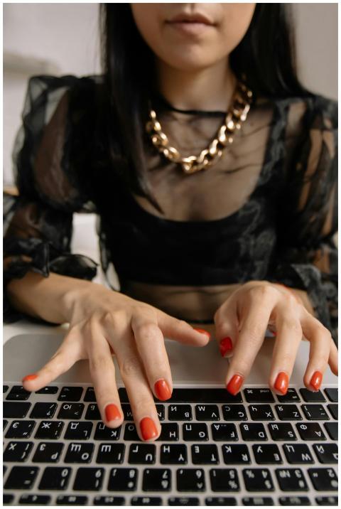 Fashionable woman wearing a chain necklace typing