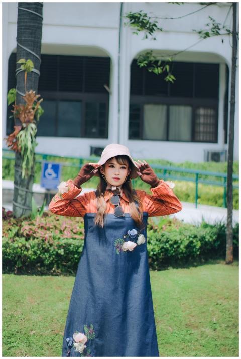 A young woman in a fashionable dress poses in a ga