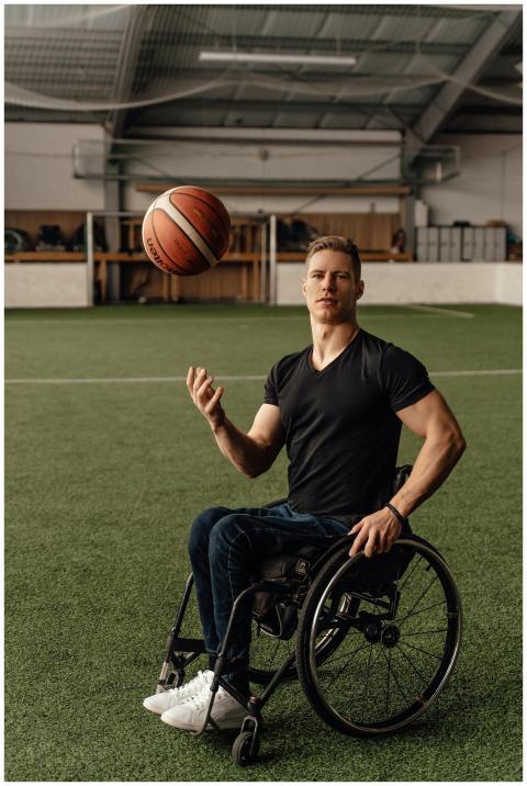 A determined young man in a wheelchair playing bas