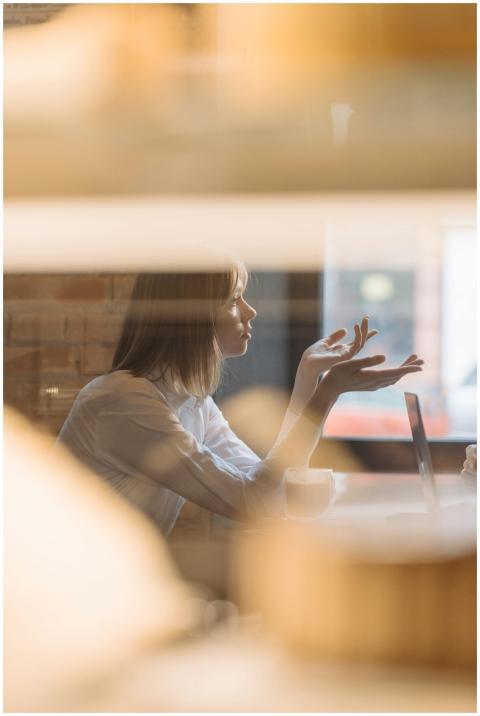 A woman sits in a cafe discussing something with i