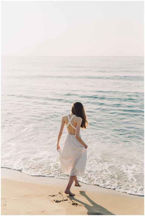 A woman walks barefoot on a sandy beach, enjoying