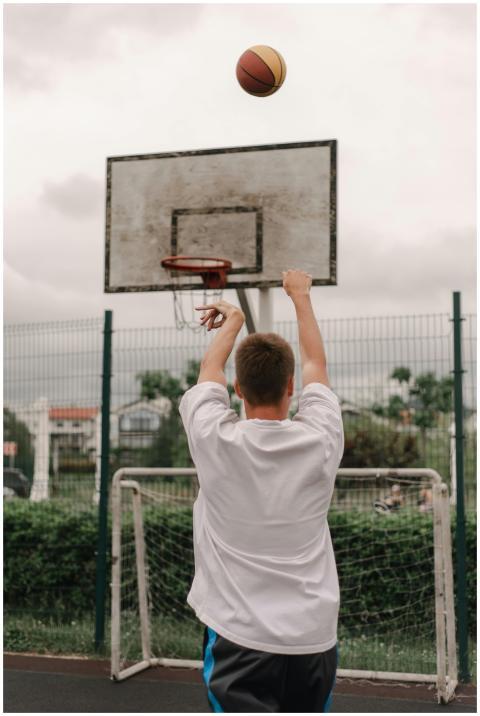 Young man shooting a basketball outdoors on a clou