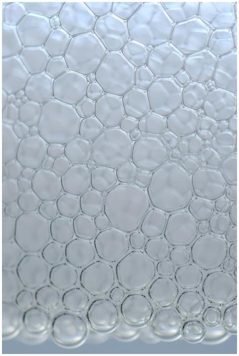 A detailed vertical close-up of delicate soap bubb