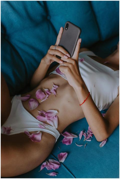 Woman in relaxed pose with petals on blue couch us