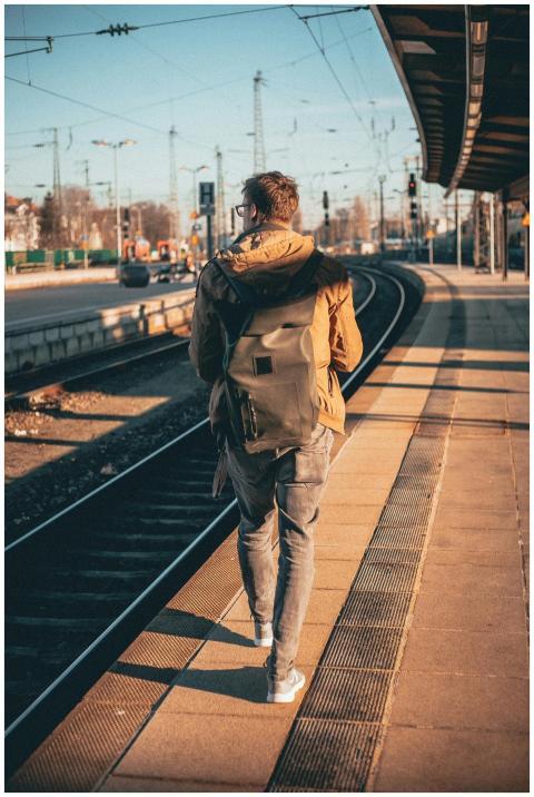 A man with a backpack walks along a train platform