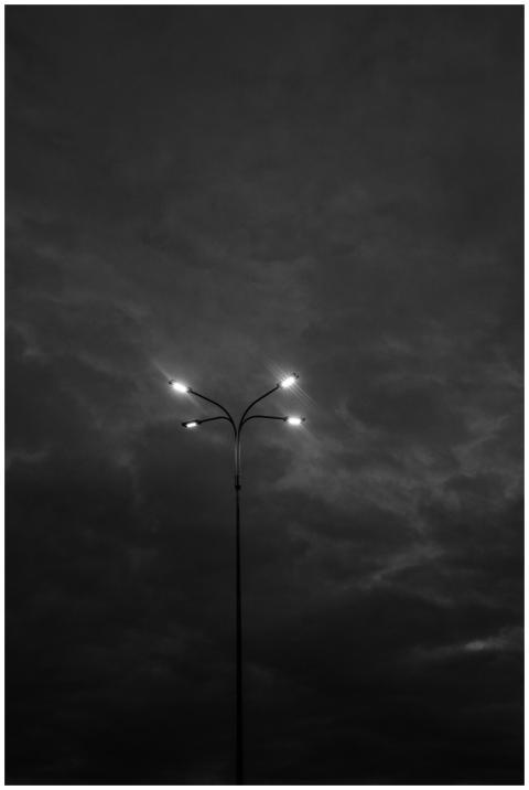 A solitary streetlight illuminates against a dark,